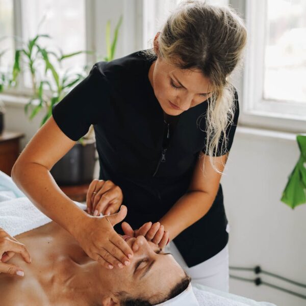 A relaxing spa session with a professional giving a facial massage therapy to a client indoors.